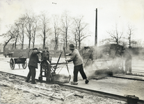 829033 Afbeelding van het instellen van de strijkmachine op de dikte van het asfalt dat gelegd moet gaan worden tijdens ...